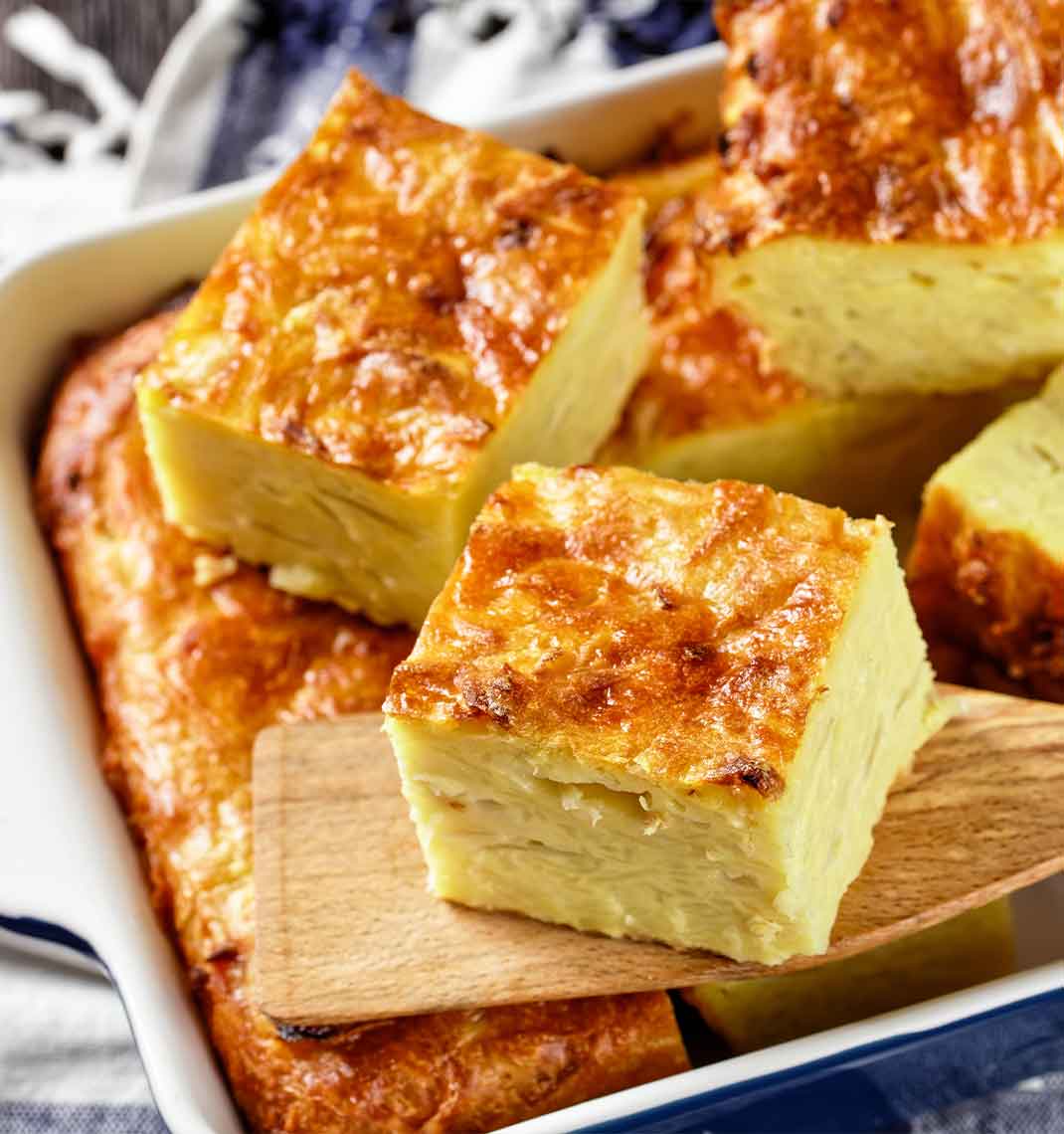 Golden squares of kugelis in a white baking dish